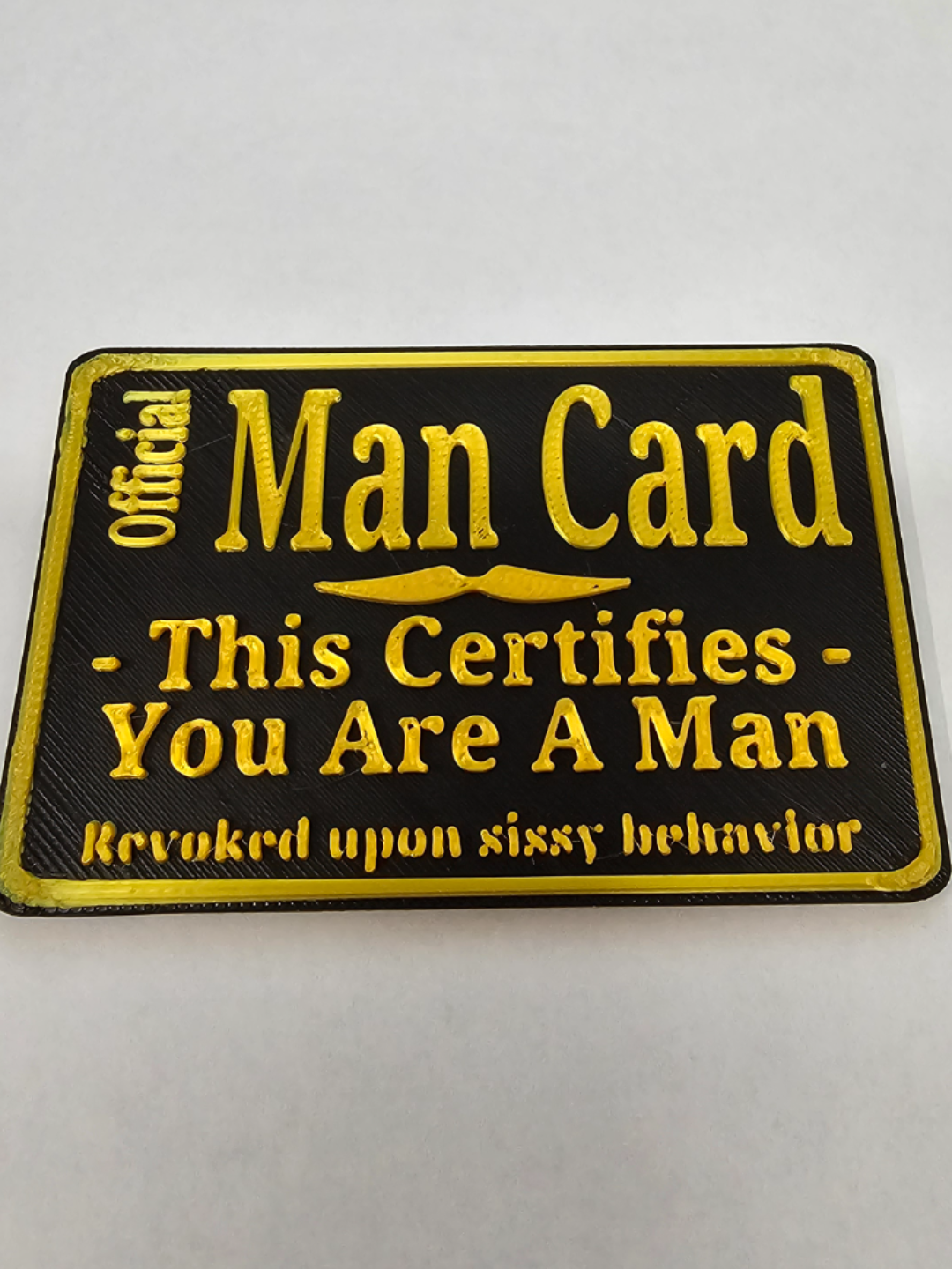 Official Man Card 3D printed plaque with raised gold lettering on black background