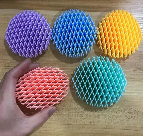 Five colorful Fidget Morf Worm sensory toys in purple, blue, orange, coral, and teal arranged on a wood surface, one held in a hand.