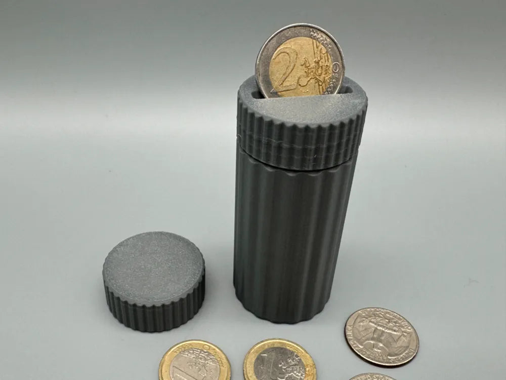 Small gray 3D-printed coin storage capsule with screw-top lid and euro coins around it