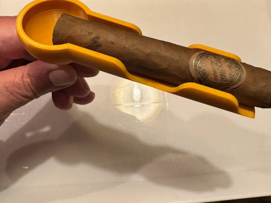 Yellow 3D printed cigar holder for golf cart with cigar inside, held by hand