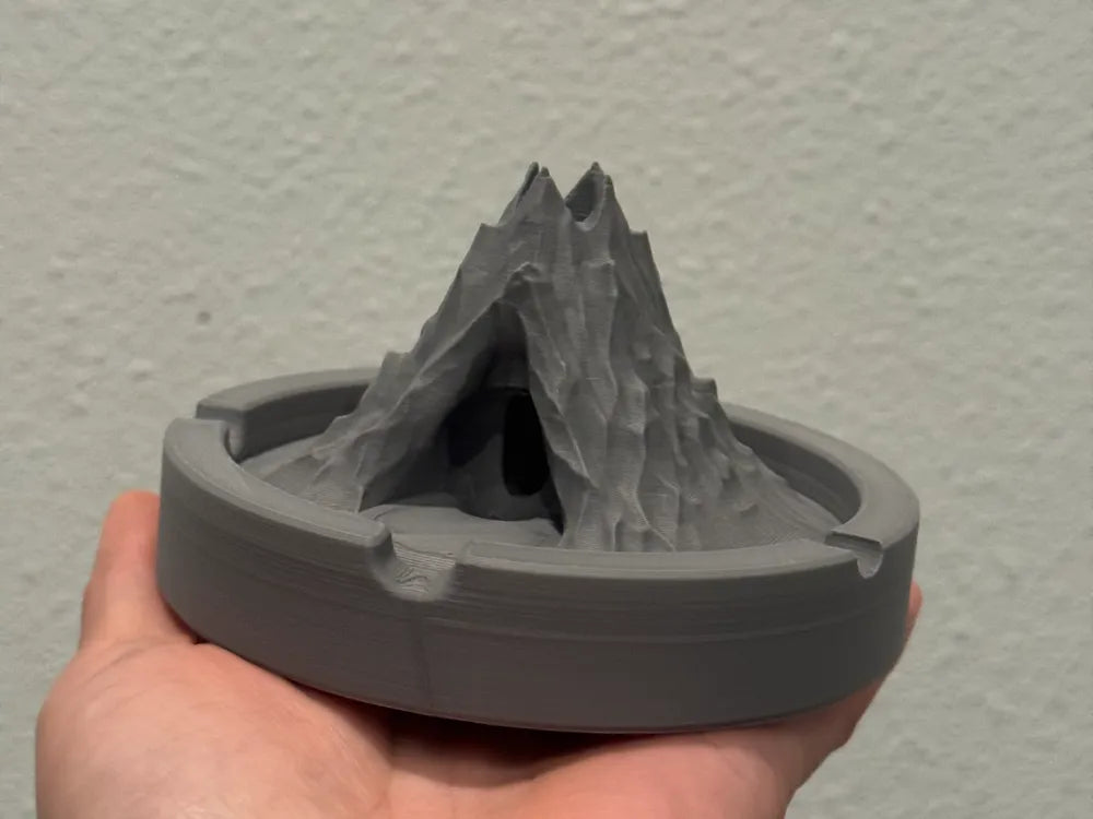 3D printed volcano-shaped ashtray held in hand showing detailed textured design and gray plastic material