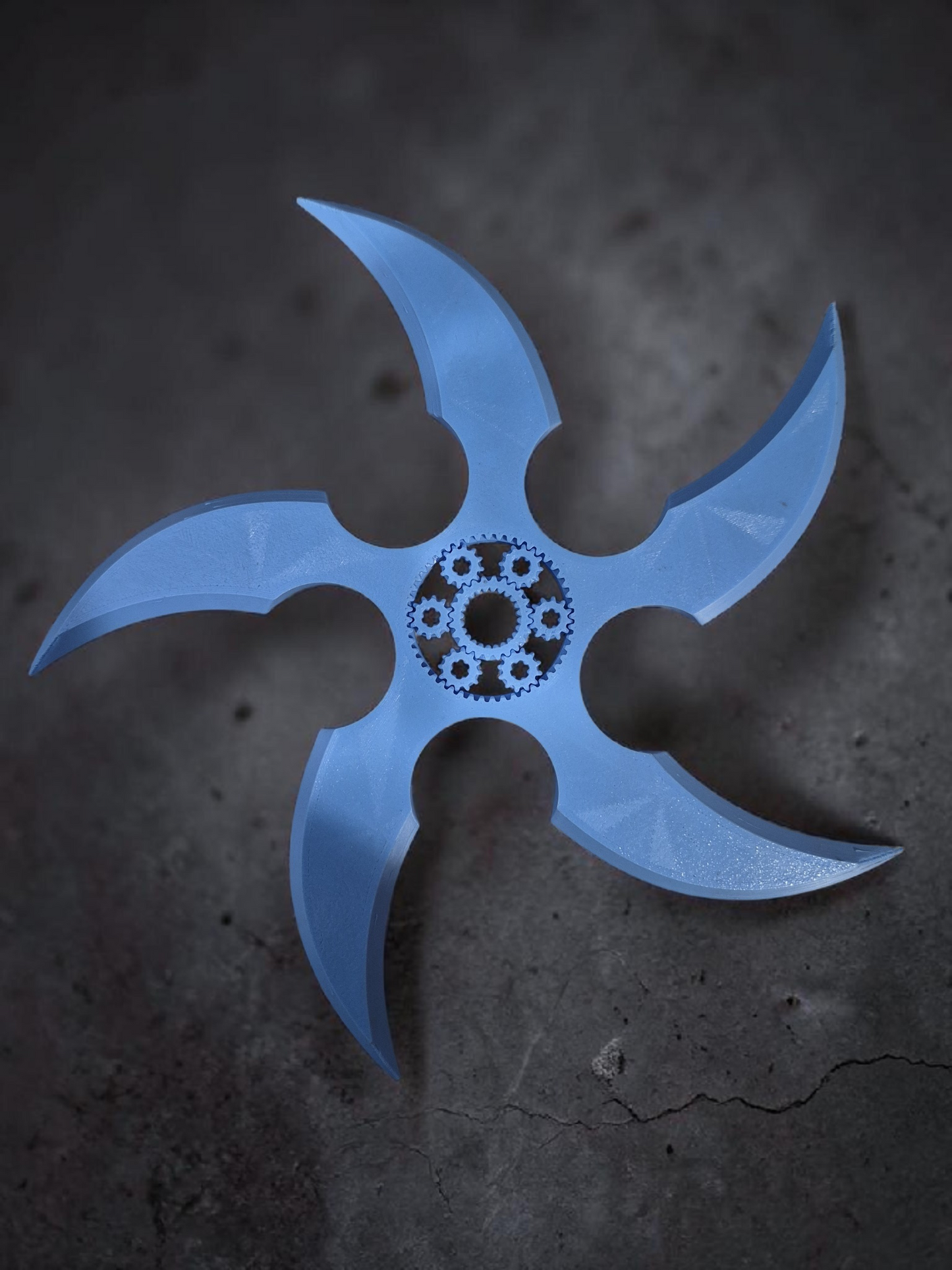 Blue 3D printed five-blade gear spinner with a central planetary gear mechanism on a dark textured background