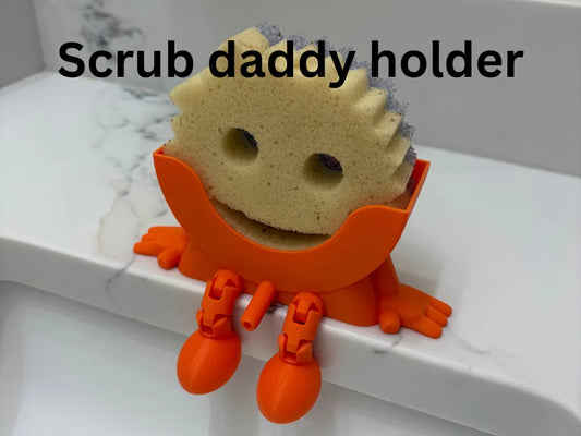 Bright orange Scrub Daddy sponge holder with flexible legs holding a sponge on a white countertop